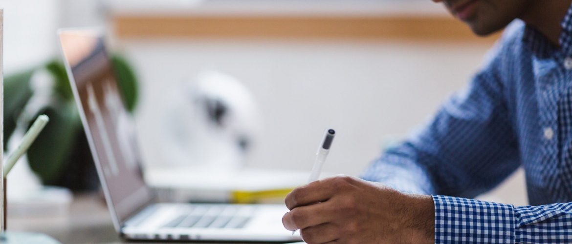 Man sat at desk with laptop & notepad