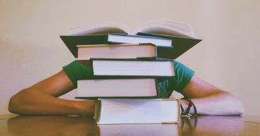 LearnOnline Course Packages: pile of books with someone behind