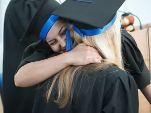 LearnOnline UCAS - two people in graduation cap and gown hugging