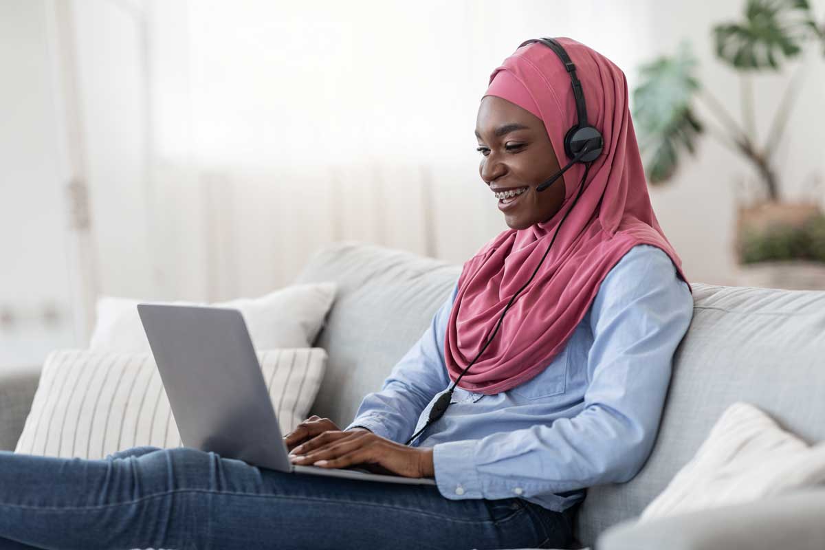 person smiling wearing a headset looking at a laptop