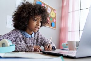 Choose your IGCSEs - 14-16 year old sat at desk writing in front of laptop