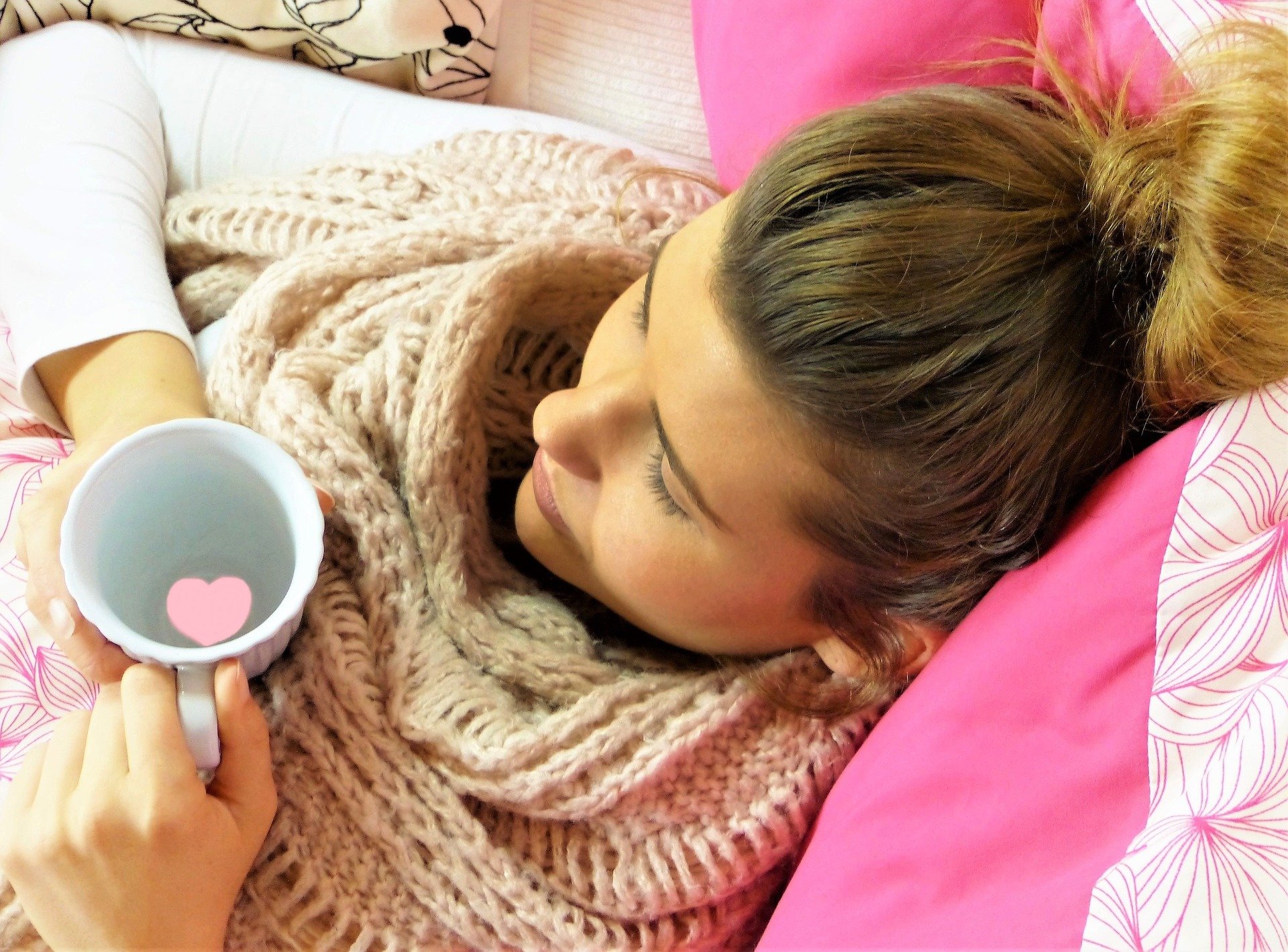 LearnOnline Safeguarding Woman sat against pink pillow with cup that has pink heart floating in it