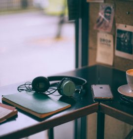 The Arts Package: table with headphones, book, phone and cup of coffee