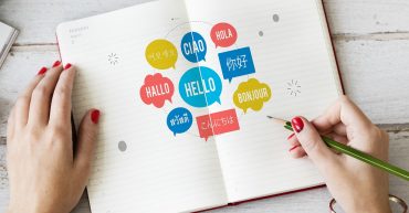 Open notebook with different languages written in speech bubbles