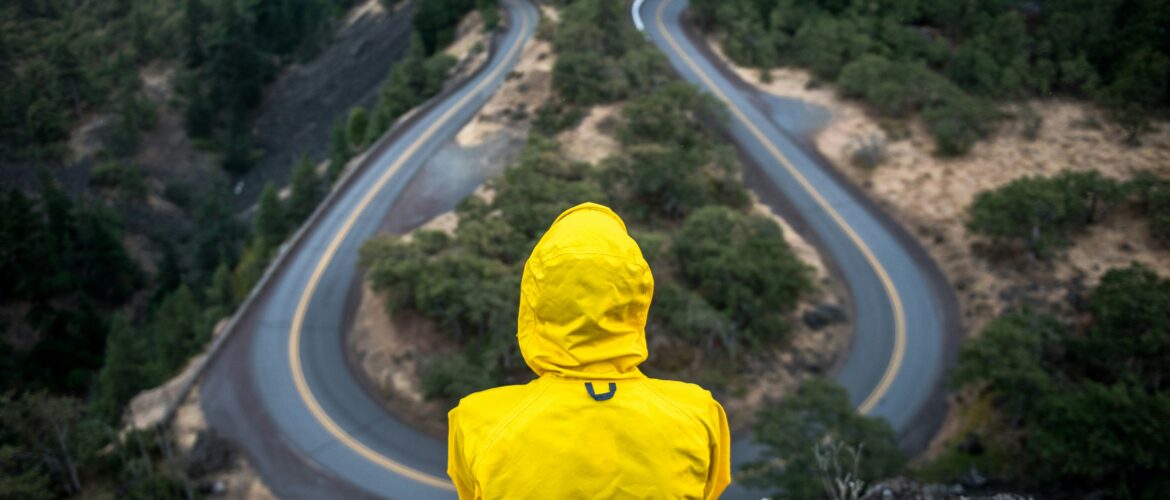 Back of person in yellow mack staring at road looping in two directions