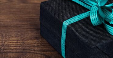 grey gift with blue ribbon on wooden table